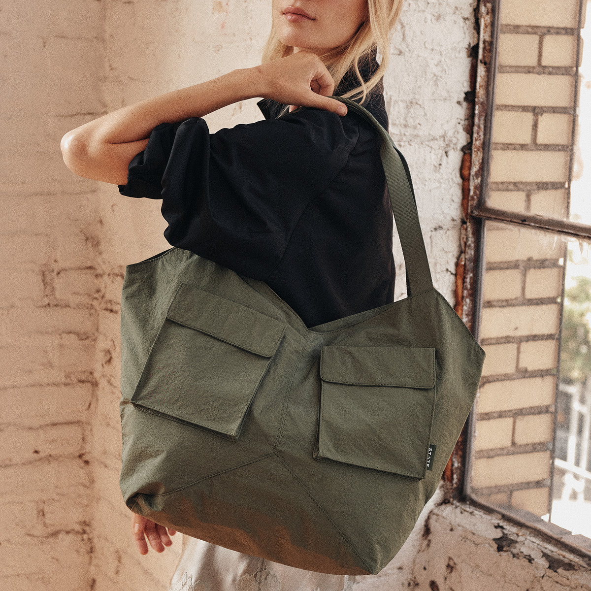 Image showing woman wearing STATE Bags Beverly Tote Crinkled Nylon Olive