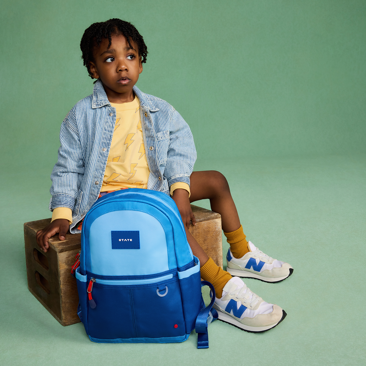 Boy sitting with state bags kane mini bakpack blue colorblock