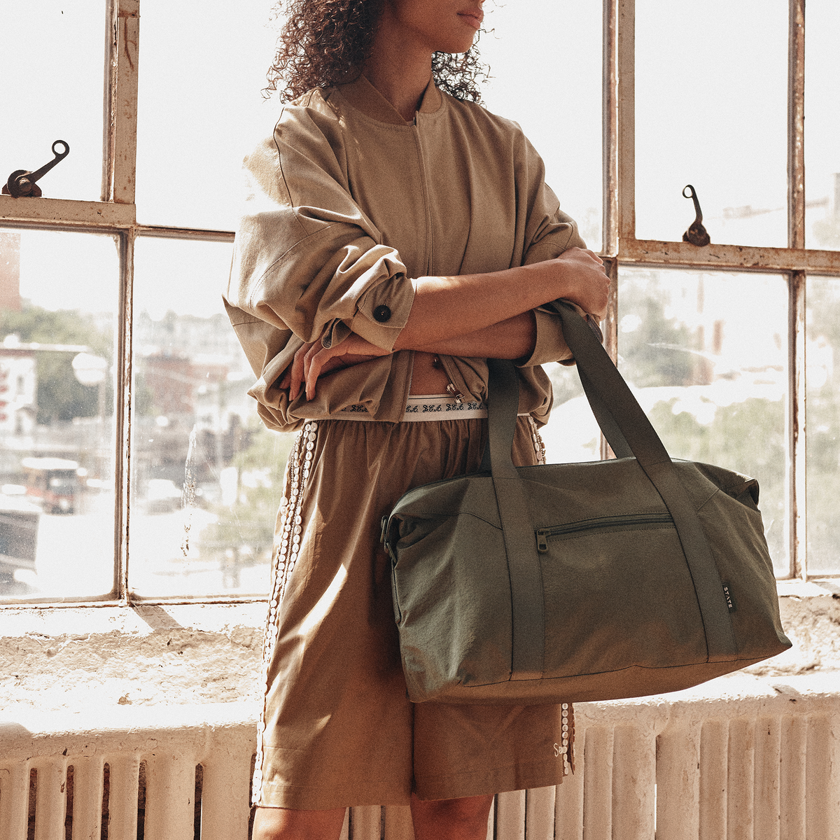 Woman wearing STATE Bags Harlow Carryall Crinkle Nylon Olive