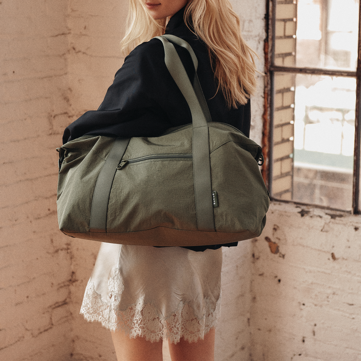 Woman wearing STATE Bags Harlow Carryall Crinkle Nylon Olive