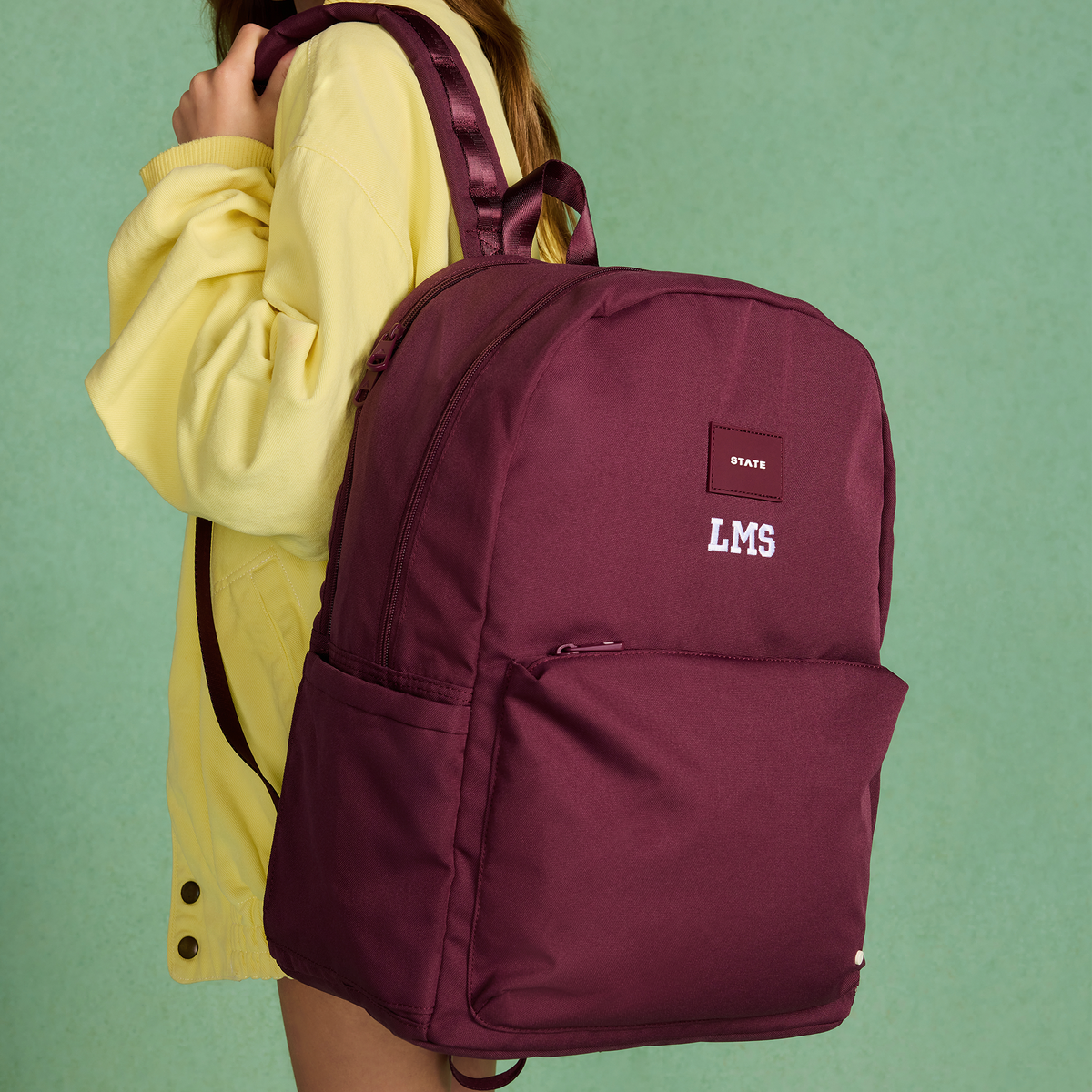 girl wearing reed backpack burgundy