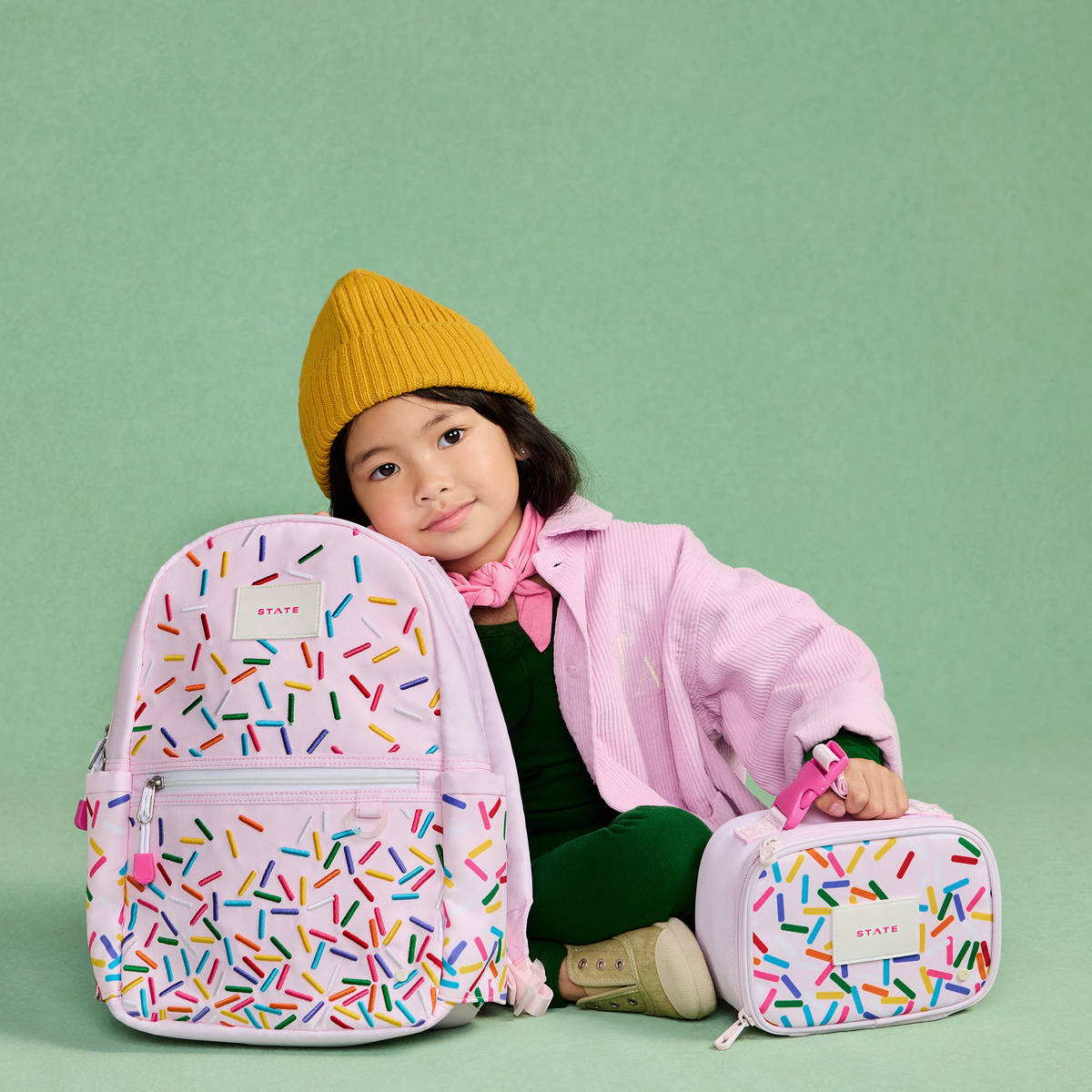 girl sitting with STATE Bags kane mini backpack sprinkles