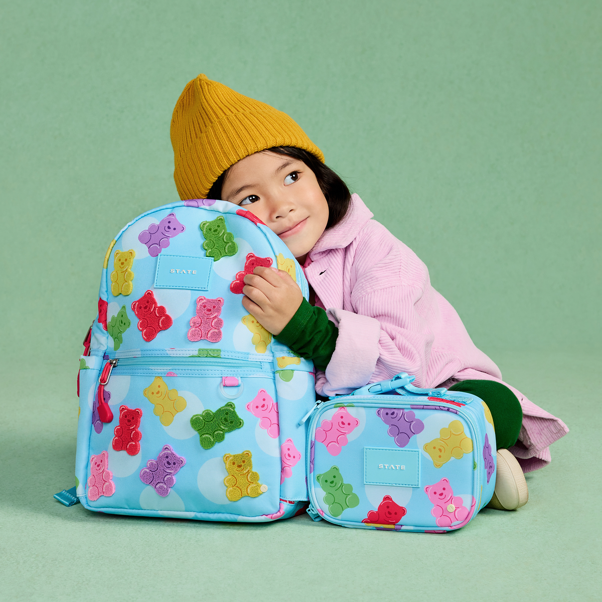 girl holding STATE Bags Kane Mini Backpack and Mini Rodgers Gummy Bears