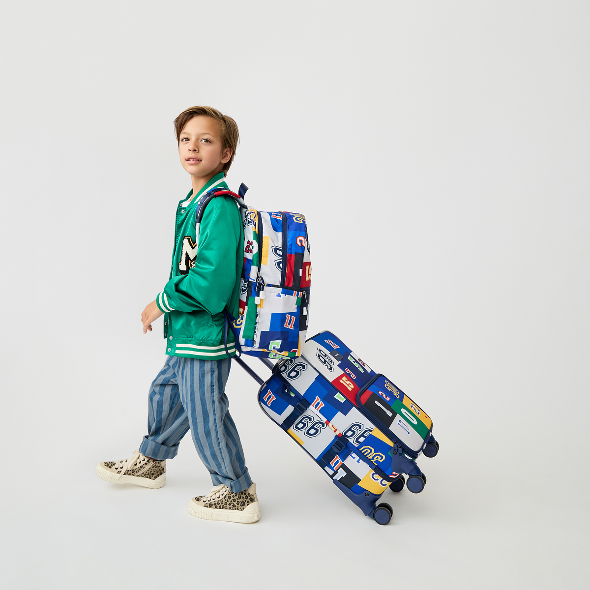 boy holding STATE Bags Logan Carry-On Suitcase Varisty Numbers